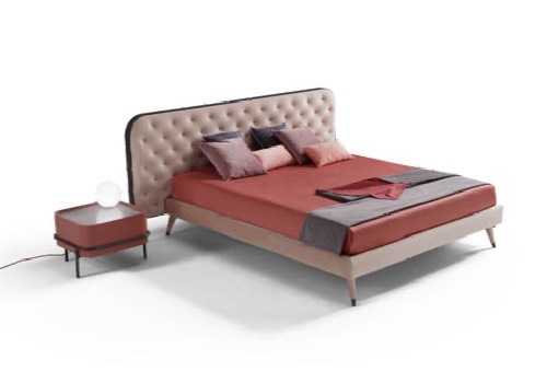cama con cabecero en ecopiel rosa, y ropa de cama roja con mesita de noche del mismo color